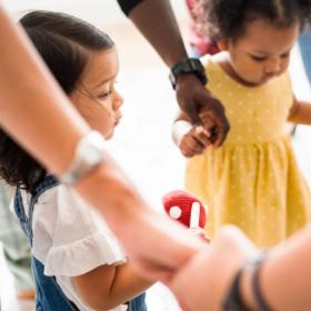 Toddlers holding hands with parents