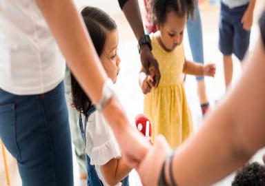 Toddlers holding hands with parents